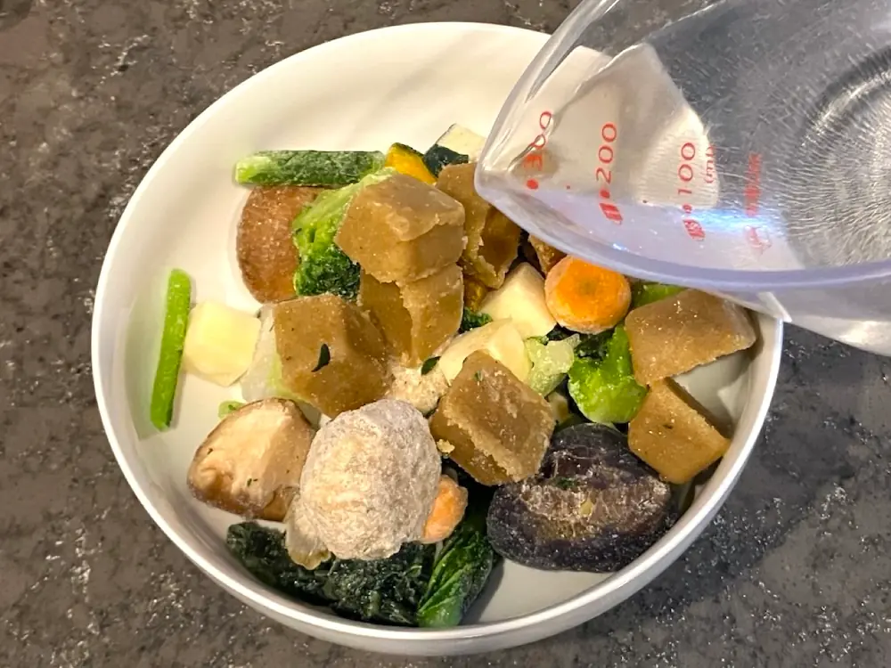 耐熱容器に入れたMISOVATION（ミソベーション）の具材に水を加えているところ